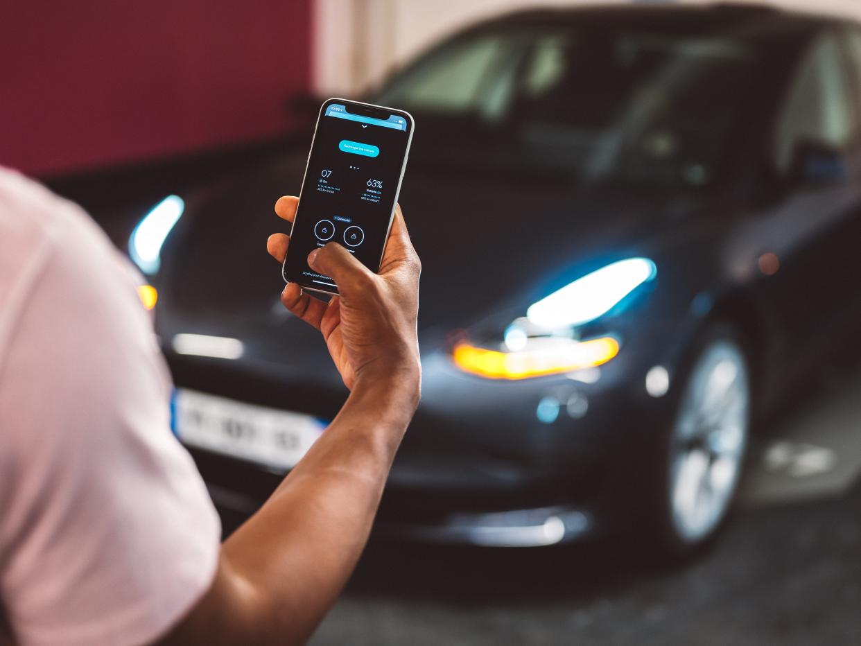 A man is unlocking a Tesla through the Virtuo app on his mobile phone.