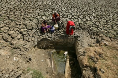 Women fetch water from an opening made by residents at a dried-up lake in Chennai