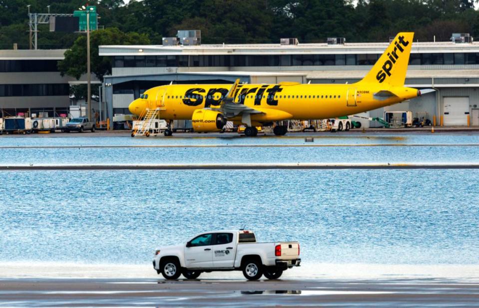 A Spirit Airlines airplane is parked as a truck drives through the flooded tarmac at Fort Lauderdale-Hollywood International Airport on Thursday, April 13, 2023.