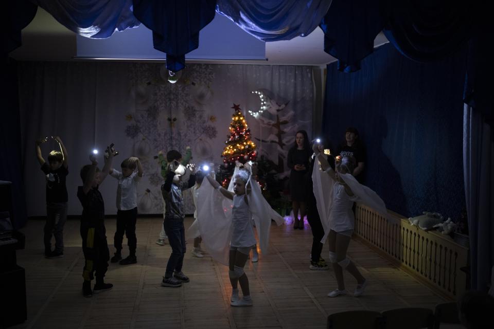 Children from the Barentsburg's school perform, some in white costumes, for Orthodox Christmas in Barentsburg, Norway, Saturday, Jan. 7, 2023. The school's English teacher, Maria Kharcheva, who recently moved here from Russia, explained the rays of light were meant to symbolize "the stars in the night sky when the Savior was born." (AP Photo/Daniel Cole)