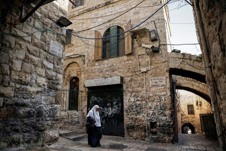 A Palestinian woman walks past a house in the Muslim Quarter of Jerusalem's Old City that was bought by Israeli settlers