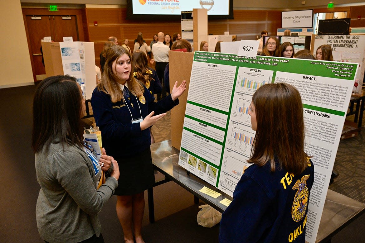 Event judge Andrea Reed, an MTSU graduate student in Mathematics and Science Education who works in the Middle Tennessee State University Tennessee STEM Education Center, listens while Oakland High freshman Kennedy Lewis, center, of Lascassas, Tenn., explains the agricultural research she and freshman Alyssa King, of Murfreesboro, Tenn., conducted during the school year. It was part of the annual Middle Tennessee STEM Innovation Hub STEM Expo, held Wednesday, April 3, in the Student Union Ballroom on the MTSU campus in Murfreesboro, Tenn.