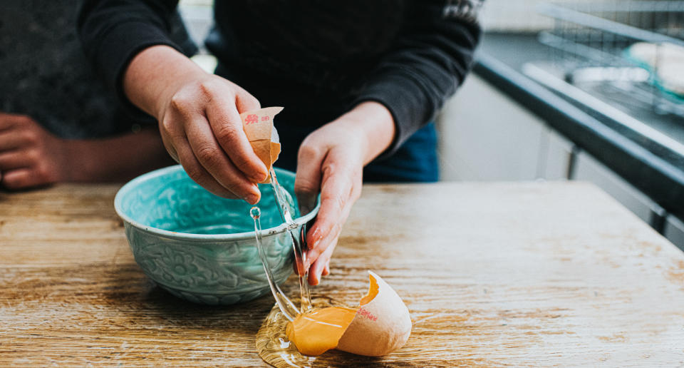 Child breaking an egg into a bowl, accidentally making a mess in the process. Space for copy.