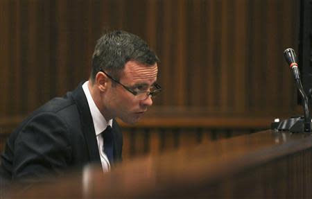 Olympic and Paralympic track star Oscar Pistorius takes notes as he sits in the dock during his trial for the murder of his girlfriend Reeva Steenkamp at the North Gauteng High Court in Pretoria, March 17, 2014. REUTERS/Siphiwe Sibeko