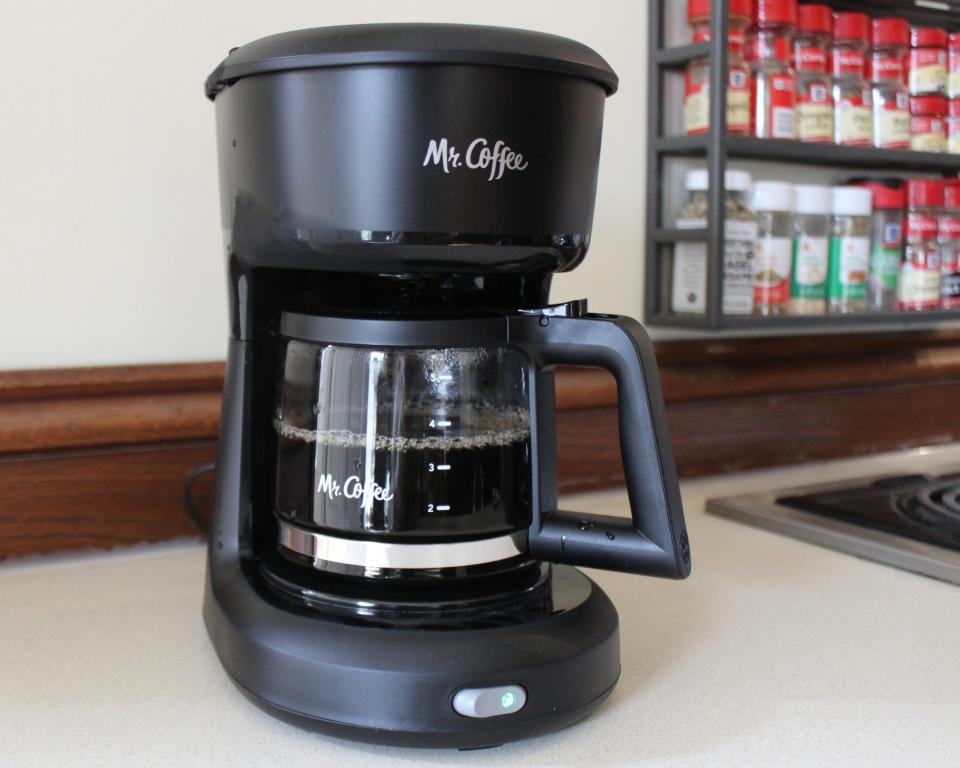 Close-up of Mr. Coffee 5-cup drip filter coffee maker adjacent to spice rack in kitchen