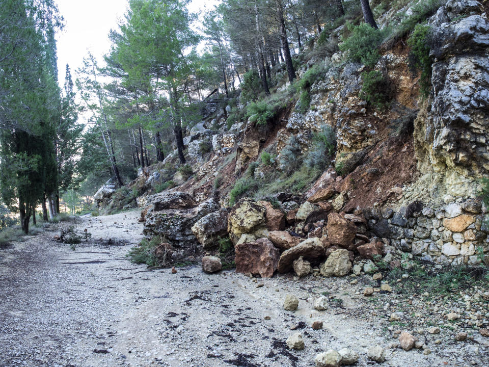 a rock slide blocking half of a dirt path