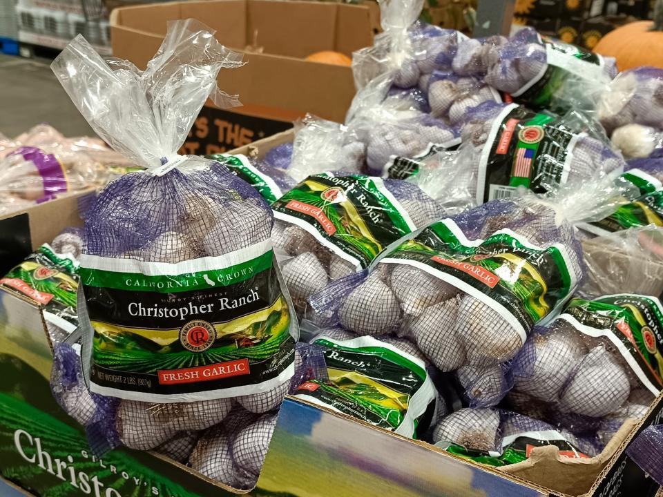 Purple and green bags of garlic piled at costco