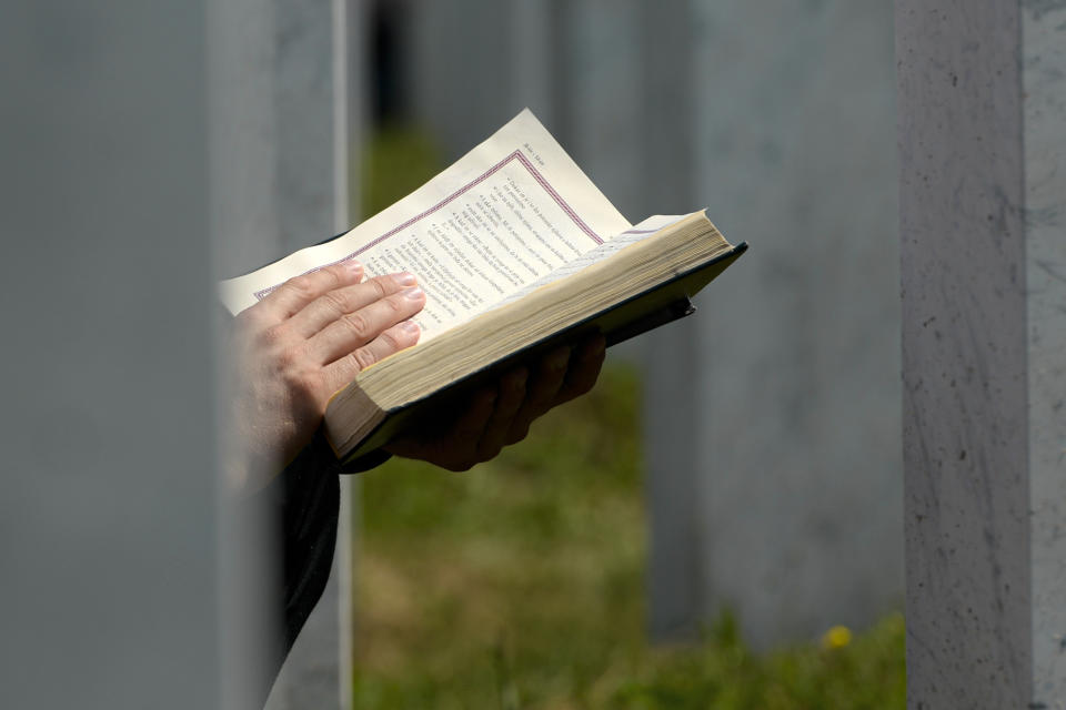 A man prays sitting between grave stones in Potocari, near Srebrenica, Bosnia, Saturday, July 11, 2020. Mourners converged on the eastern Bosnian town of Srebrenica for the 25th anniversary of the country's worst carnage during the 1992-95 war and the only crime in Europe since World War II that has been declared a genocide. (AP Photo/Kemal Softic)