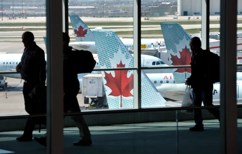 Passengers walk past Air Canada planes on the runway at Pearson International Airport in Toronto