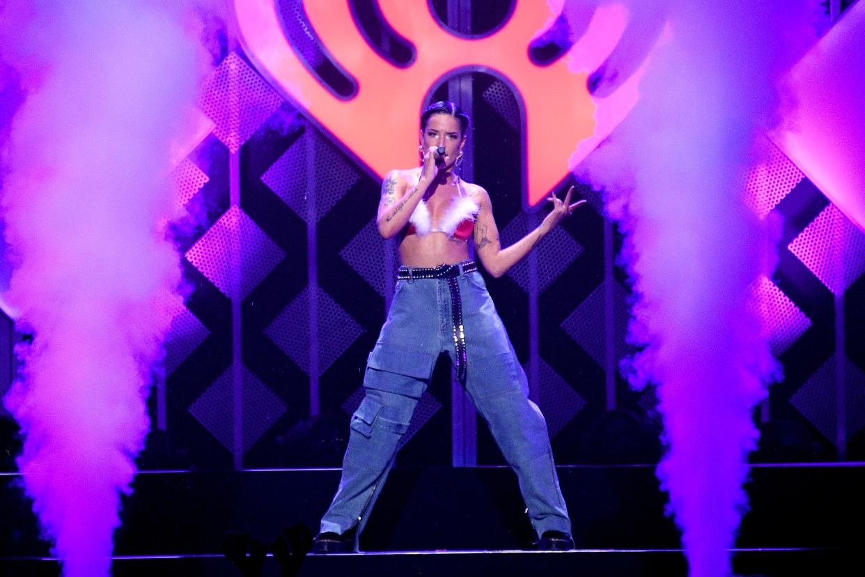 Halsey holds a microphone while posing on stage