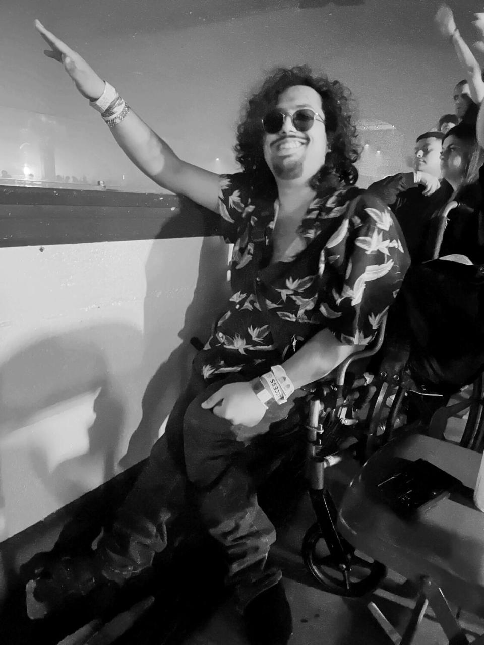 Saptarshi Majumdar, with long hair and a beard, sits in a wheelchair overlooking the balcony at a concert venue.