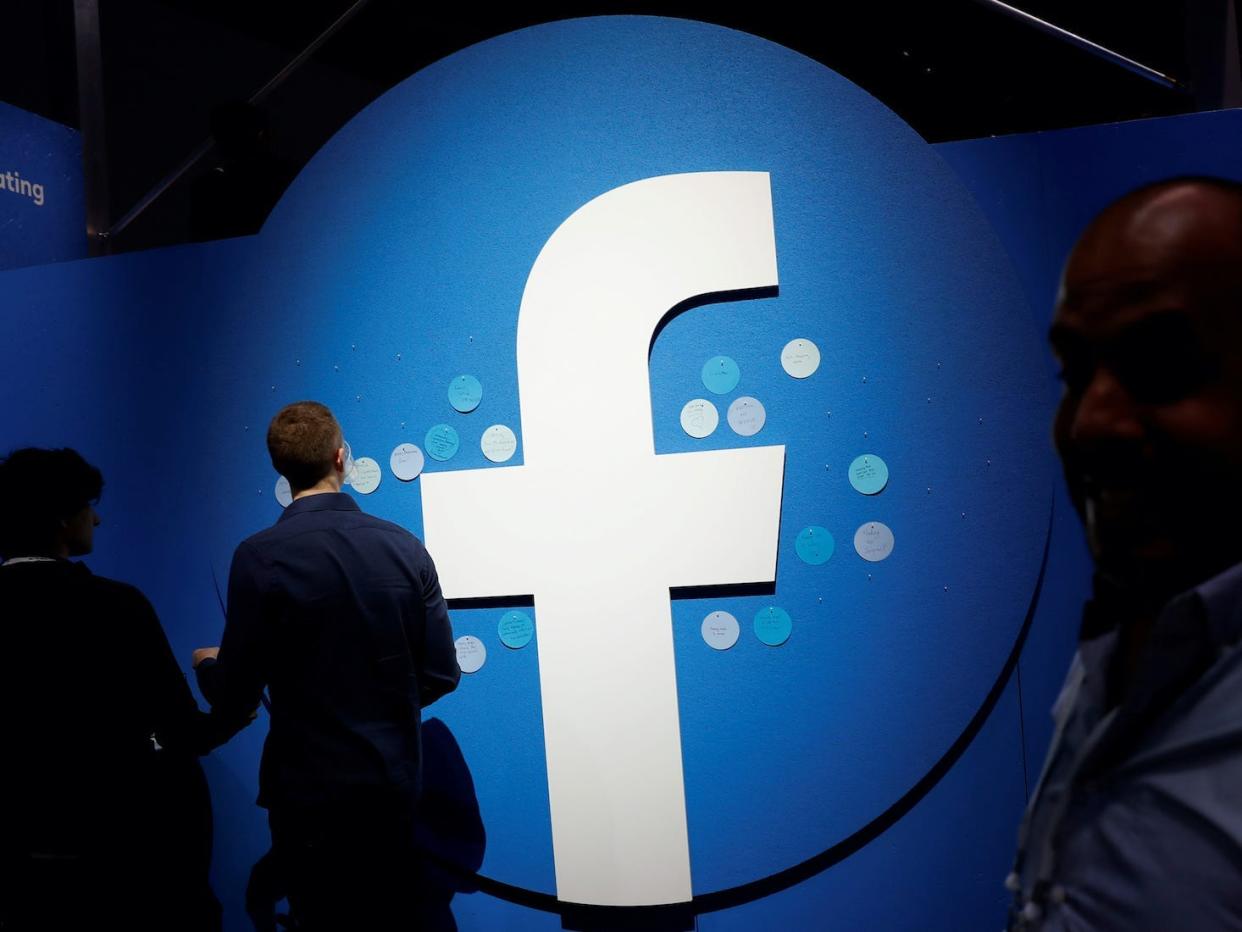 Attendees walk past a Facebook logo during Facebook Inc's F8 developers conference in 2019.