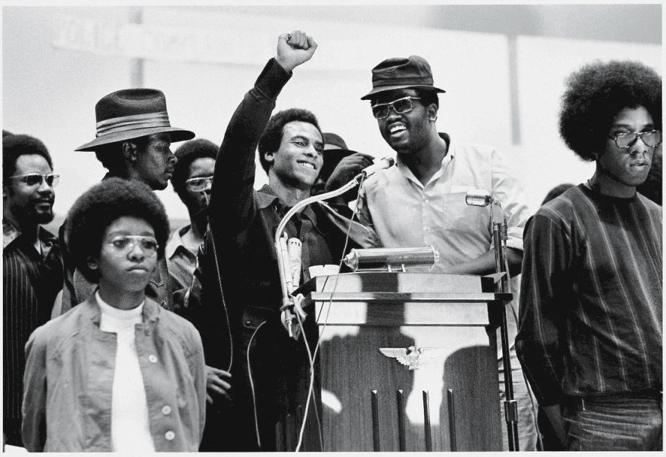 Black Panther Party co-founder Huey P. Newton (1942 - 1989) (center) smiles as he raises his fist from a podium at the Revolutionary People's Party Constitutional Convention, Philadelphia, Pennsylvania, early September 1970.