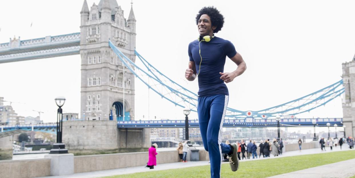 a young man jogging past tower bridge in london