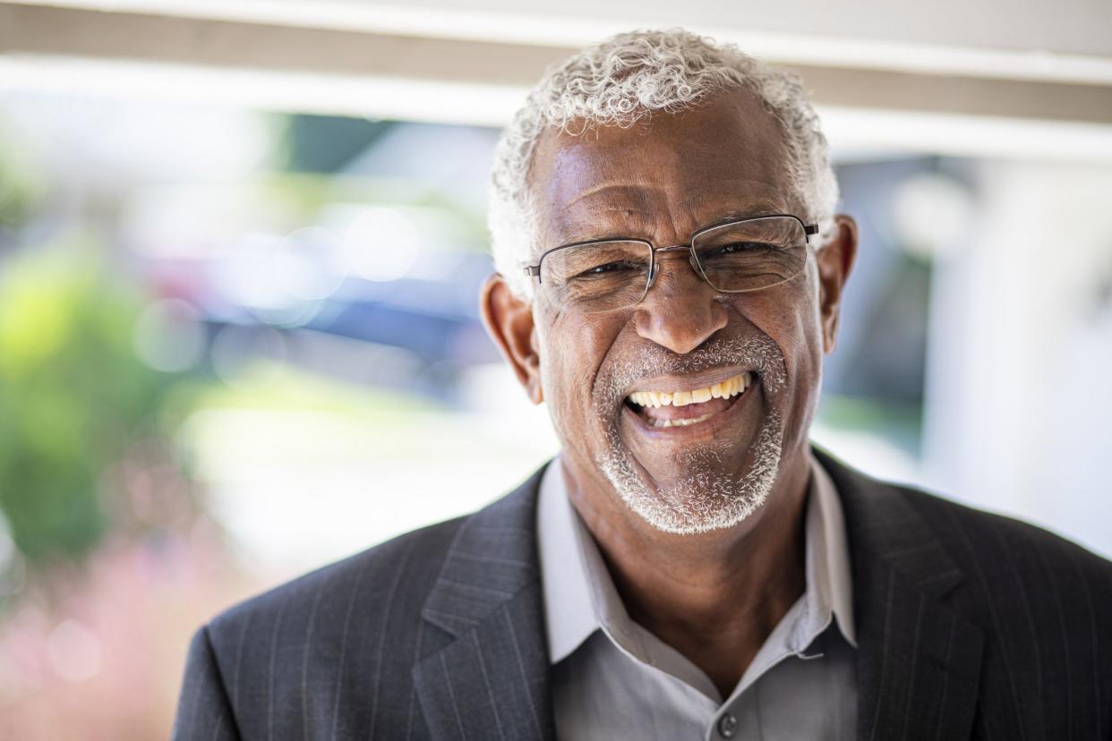 A senior black man canvassing door to door smiles