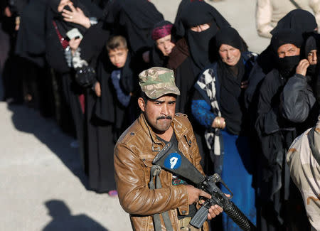 An Iraqi soldier holds a gun in front of women who are waiting food to be distributed by an Iraqi government organisation in Mosul, Iraq November 24, 2016. REUTERS/Goran Tomasevic