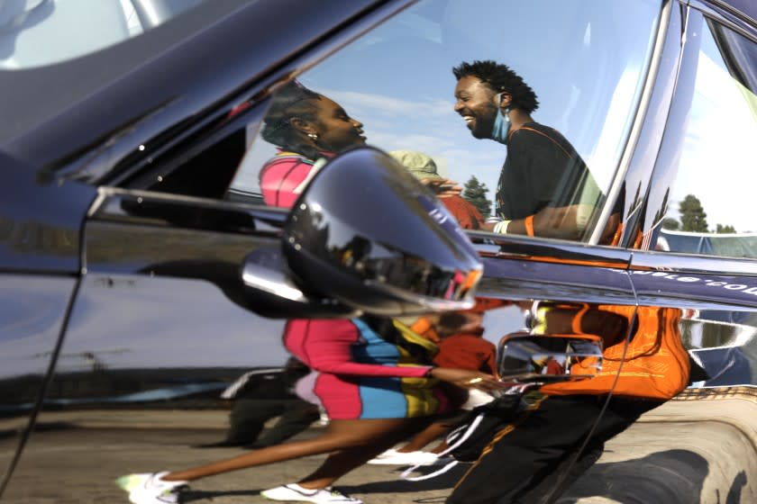 LOS ANGELES, CA - SEPTEMBER 25, 2021 - - Latasha, left, and Dave Giles II, reflected in a Polestar 2 Battery Electric Vehicle, enjoy a conversation at the, "Black To The Future," tech event in the business district of Leimert Park on September 25, 2021. The event was highlighting Black technology through a speakers forums and other venues to share the latest technology created by Black techs. Giles was on hand to talk about his Black owned APP, "CON VOZ." Home sales are soaring in Leimert Park causing fear that the residents can no longer afford to buy homes in the neighborhood. (Genaro Molina / Los Angeles Times)