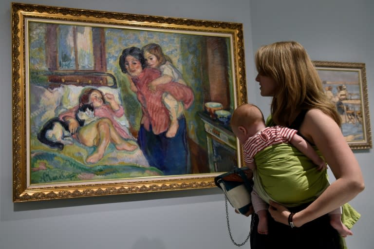 Visitors look at a painting in the newly-opened museum of Russian impressionist art in Moscow on May 28, 2016