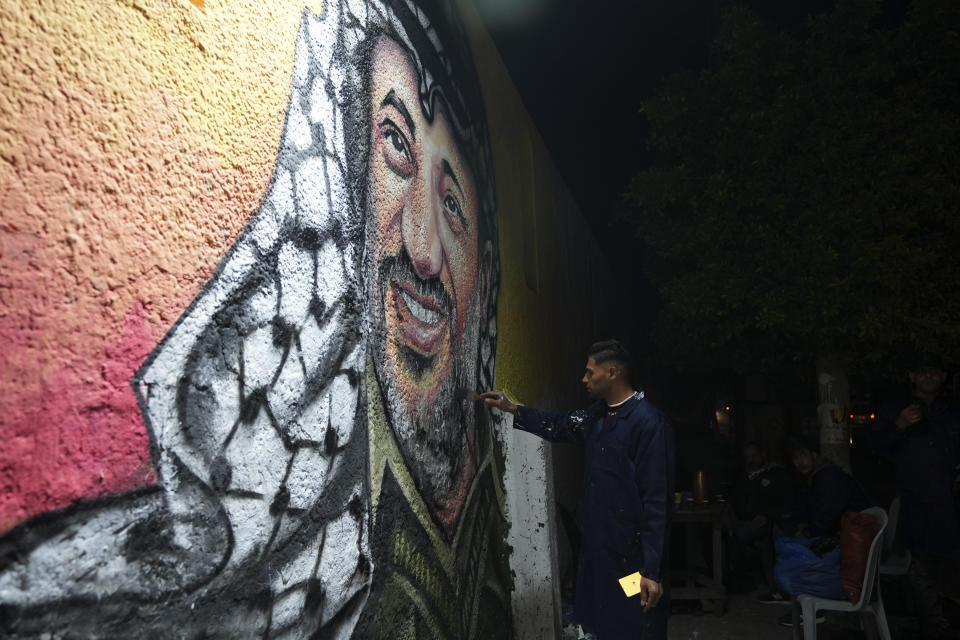 A Palestinian artist paints a portrait of of the late Palestinian president Yasser Arafat, on a wall in preparation of celebration of 58th Fatah anniversary, at the main square in Gaza City, Friday, Dec. 30, 2022. (AP Photo/Adel Hana)