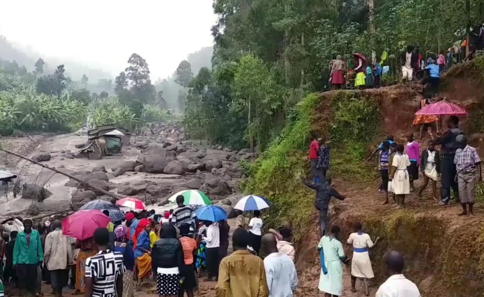 In this image made from video, residents look at a river filled with mud in Bududa District, Uganda, Friday, Oct. 12, 2018. At least 30 people died in mudslides triggered by torrential rains in a mountainous area of eastern Uganda that is prone to such disasters, a Red Cross official said Friday. More victims were likely to be discovered when rescue reams access all the affected areas in the foothills of Mount Elgon, said Red Cross spokeswoman Irene Nakasiita. (AP Photo)