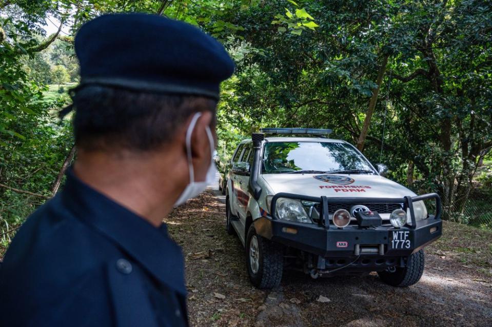 File picture shows a policeman cop standing guard as a forensic vehicle leaves the main entrance of the location where the body of Franco-Irish teenager Nora Anne Quoirin was found, near the Dusun resort, in Seremban on August 13, 2020. — AFP pic