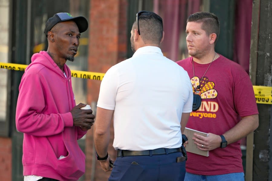 Emmitt Wilson, left, father of a 14-year-old shooting victim, speaks to Tampa police officers in the Ybor City section of Tampa, Fla., after a shooting early Sunday, Oct. 29, 2023. A fight between two groups turned deadly in a shooting during Halloween festivities. (AP Photo/Chris O’Meara)
