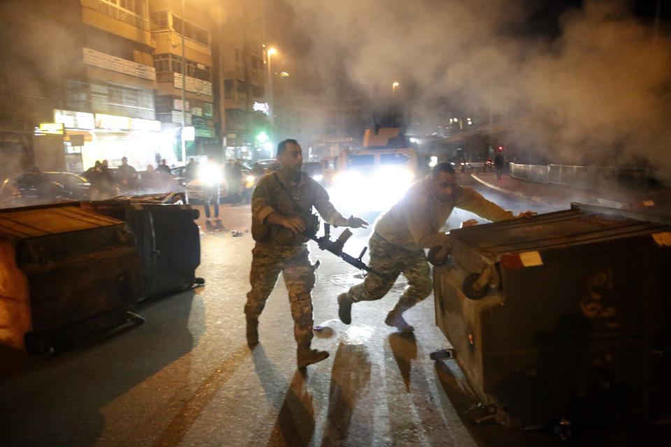 Lebanese army soldiers remove garbage containers that were set on fire by anti-government protesters to block roads in Beirut, Lebanon, Tuesday, Jan. 21, 2020. Lebanon's prime minister designate Hassan Diab announced Tuesday a new government for the crisis-hit country, breaking a months-long impasse amid ongoing mass protests against the country's ruling elite. (AP Photo/Hussein Malla)