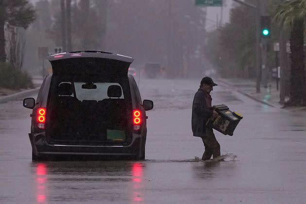 A motorist removes belongings from his vehicle after becoming stuck in a flooded street on Sunday in Palm Desert, California.