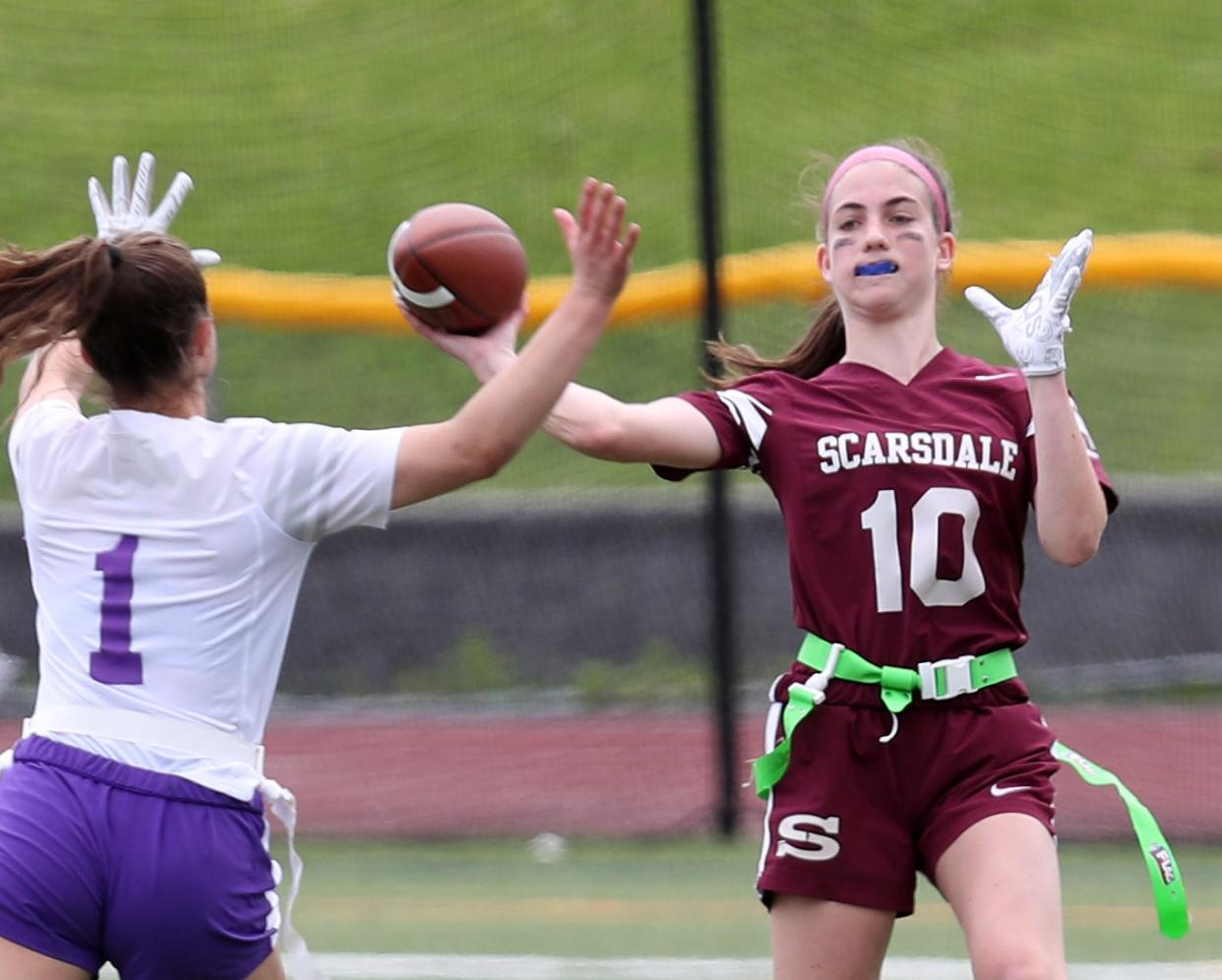 Scarsdale's Ivy Boockvar (10) gets a pass off despite pressure from New Rochelle's Stella Ziogas (1) during the Section 1 flag football Section 1 championship at Lakeland High School in Shrub Oak May 18, 2024. Scarsdale won the game 21-8.