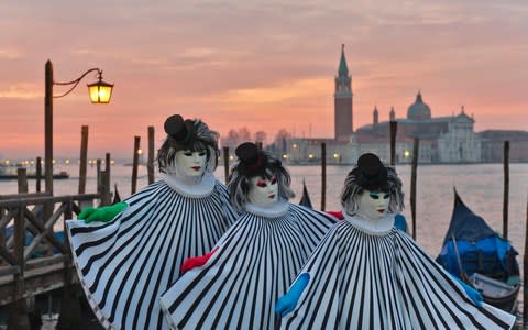 Three people in Venetian carnival costumes - Credit: Getty