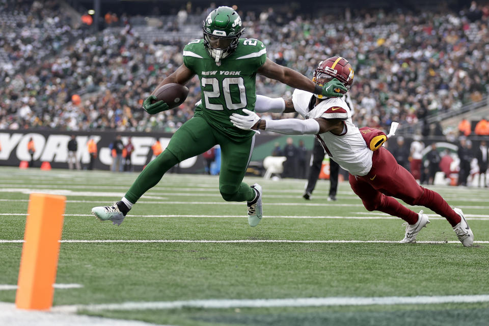 New York Jets running back Breece Hall (20) stiff arms Washington Commanders safety Kamren Curl (31) on his way to a touchdown during the second quarter of an NFL football game, Sunday, Dec. 24, 2023, in East Rutherford, N.J. (AP Photo/Adam Hunger)