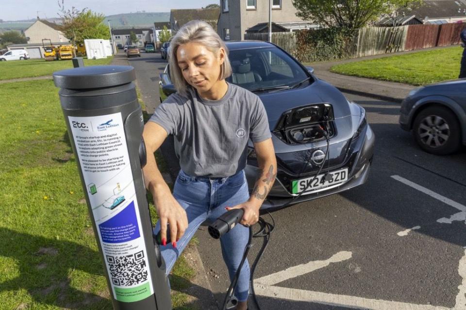 a person charging an ev from a former green cabinet in scotland