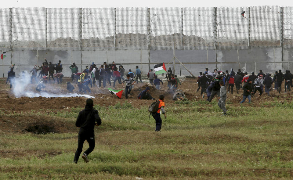 Protesters run to cover from teargas fired by Israeli troops near fence of Gaza Strip border with Israel, marking first anniversary of Gaza border protests east of Gaza City, Saturday, March 30, 2019. Tens of thousands of Palestinians gathered Saturday at rallying points near the Israeli border to mark the first anniversary of weekly protests in the Gaza Strip, as Israeli troops fired tear gas and opened fire at small crowds of activists who approached the border fence. (AP Photo/Adel Hana)
