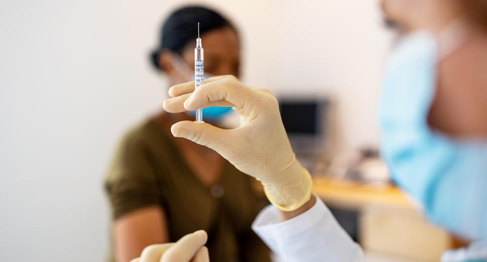 Close up of doctor preparing injection for vaccination in clinic. Hands of a female doctor preparing flu injection.