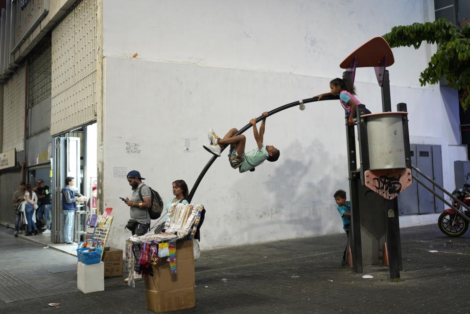 Children play on a jungle gym along Sabana Grande boulevard in Caracas, Venezuela, Wednesday, March 1, 2023. A generation of children in Venezuela have only known a country in crisis, plagued over the last decade or more by shortages and inflation. (AP Photo/Ariana Cubillos)
