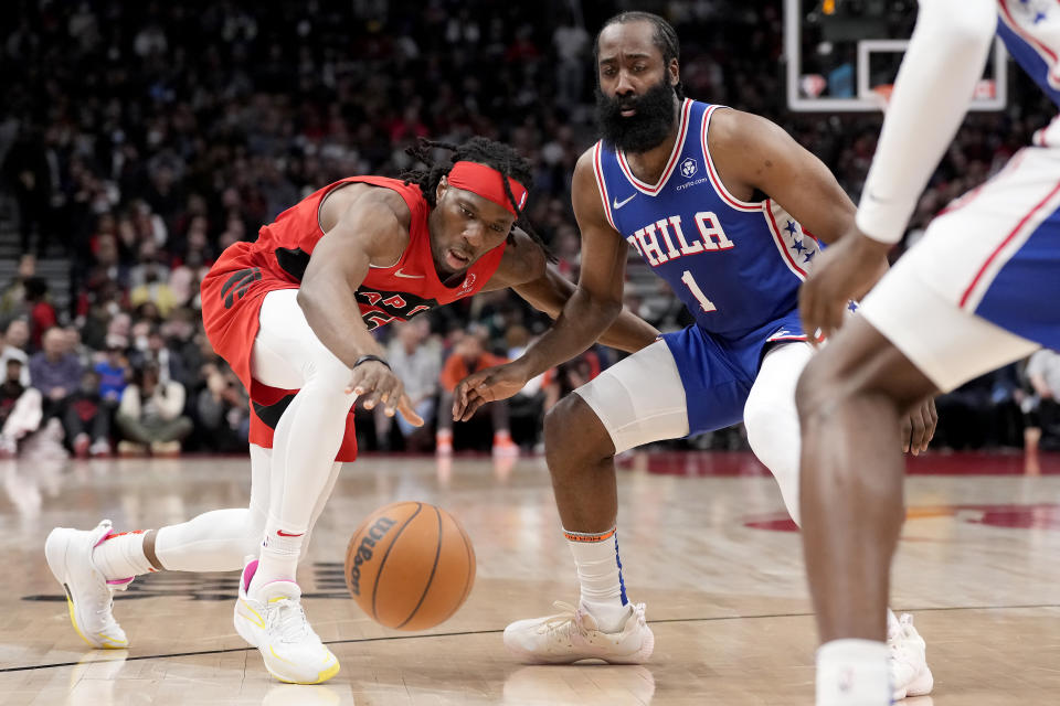 Toronto Raptors forward Precious Achiuwa (5) reaches for the ball next to Philadelphia 76ers guard James Harden (1) during the first half of an NBA basketball game Thursday, April 7, 2022, in Toronto. (Frank Gunn/The Canadian Press via AP)