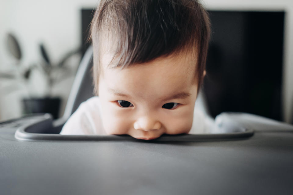 Playful baby biting the high chair table