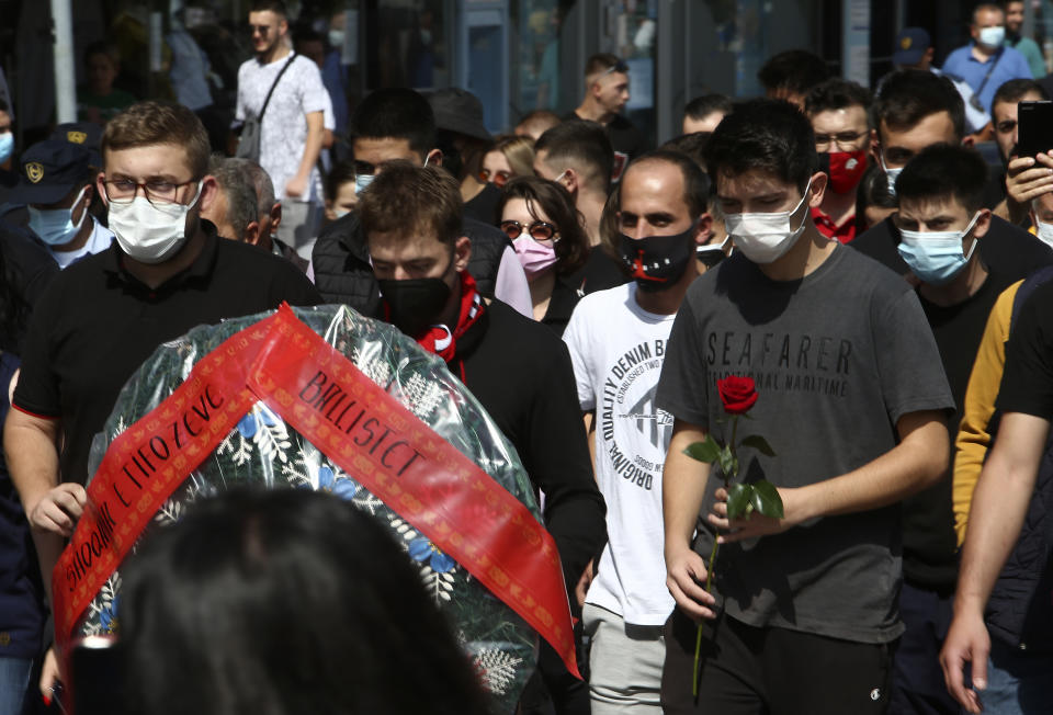 Young men carry a wreath and flowers while marching in silence to honor the victims in the burned out makeshift hospital in North Macedonia's northwestern town of Tetovo, Saturday, Sept. 11, 2021. Hundreds of people have marched Saturday in northwestern town of Tetovo to honor their 14 countrymen killed in a deadly fire that broke earlier this week and destroyed COVID-19 field hospital. (AP Photo/Boris Grdanoski)