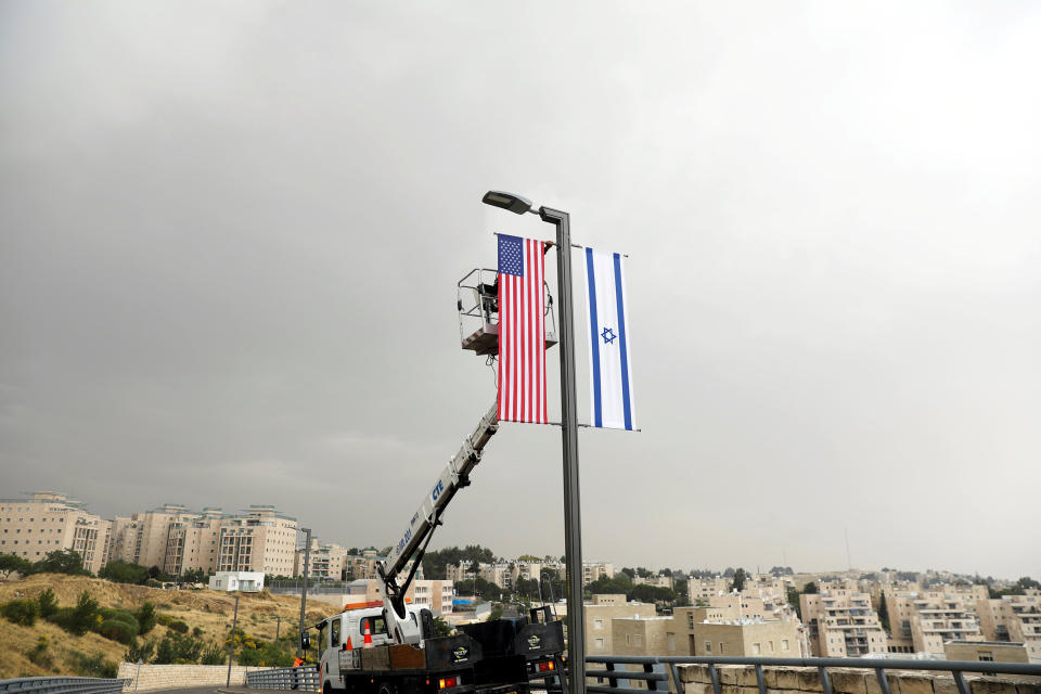 A worker on a crane hangs a U.S. flag alongside an Israeli flag, next to the entrance to the U.S. consulate in Jerusalem, on May 7, 2018.