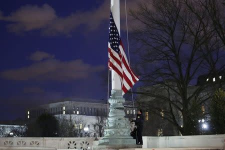 Capitol Hill police officers lower the U.S. flag at the Supreme Court in Washington D.C. after the death of U.S. Supreme Court Justice Antonin Scalia, February 13, 2016. Conservative Justice Scalia, 79, has died, Texas Governor Greg Abbott said. REUTERS/Carlos Barria