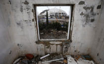 A picture shot through the window of a house that has to be torn down as it is within the perimeters of the Olympic Park shows the Olympic stadium for the Sochi 2014 Winter Olympics at the Olympic Park in Adler, near Sochi February 18, 2013. Although many complexes and venues in the Black Sea resort of Sochi mostly resemble building sites that are still under construction, there is nothing to suggest any concern over readiness. Construction will be completed by August 2013 according to organizers. The Sochi 2014 Winter Olympics opens on February 7, 2014. REUTERS/Kai Pfaffenbach (RUSSIA - Tags: BUSINESS CONSTRUCTION ENVIRONMENT SPORT OLYMPICS) - RTR3DYR7