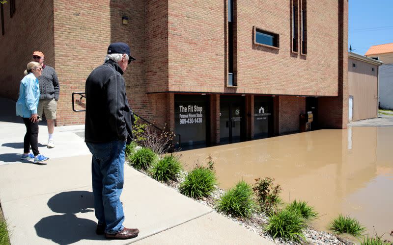 Residents look at a flooded street along the Tittabawassee River, after several dams breached, in downtown Midland