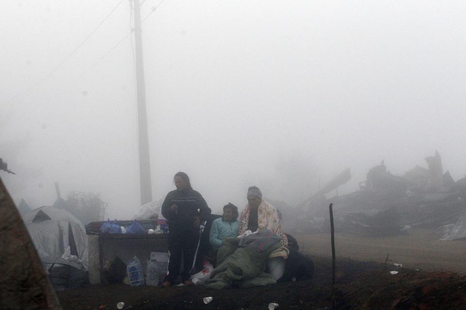 Una familia permanece en un campamento improvisado junto a las ruinas de su casa en Valparaíso, Chile, el martes 15 de abril de 2014. Al menos 15 personas han perdido la vida en los incendios que comenzaron el sábado pasado, que además arrasaron más de 2.900 viviendas y dejado 12.500 damnificados. (Foto AP/Luis Hidalgo).