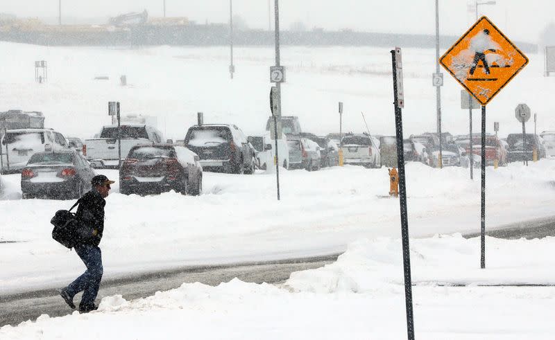 FILE PHOTO: A traveler makes his way to a shuttle stop after a snowstorm at Denver International Airport