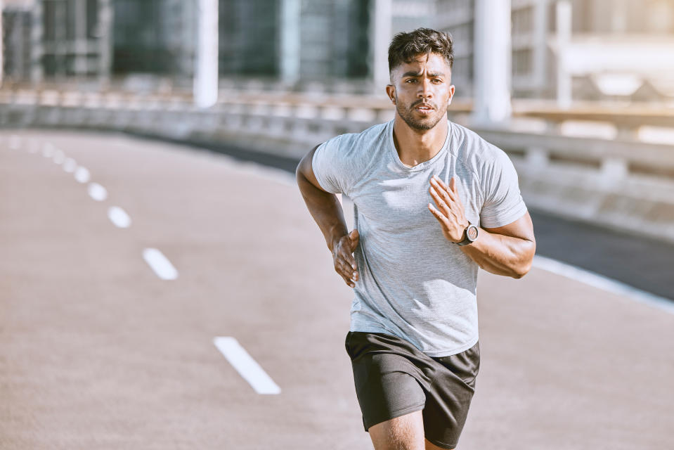 A fit young man runs around a track.