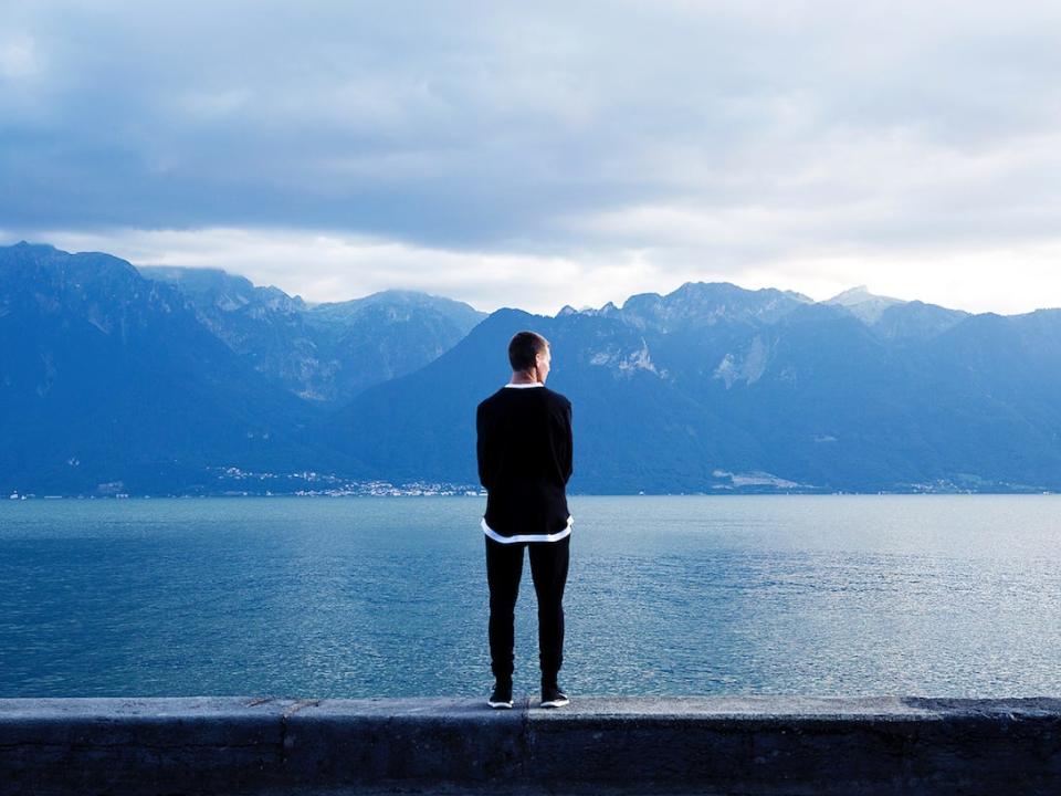 man concentrating thinking focusing pensive alone nature mountains water sky