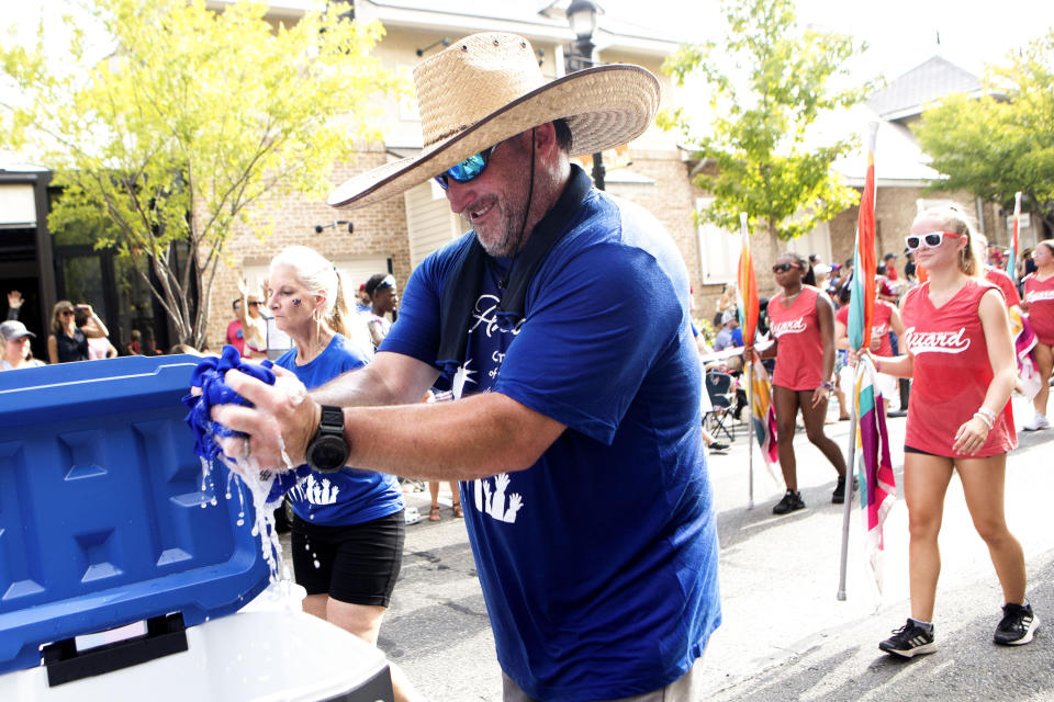 James Latham wrings out a wet towels to give to parade goers during the annual South Montgomery County 4th of July Parade at Market Street, Tuesday, July 4, 2023, in The Woodlands, Texas. (Jason Fochtman/Houston Chronicle via AP)