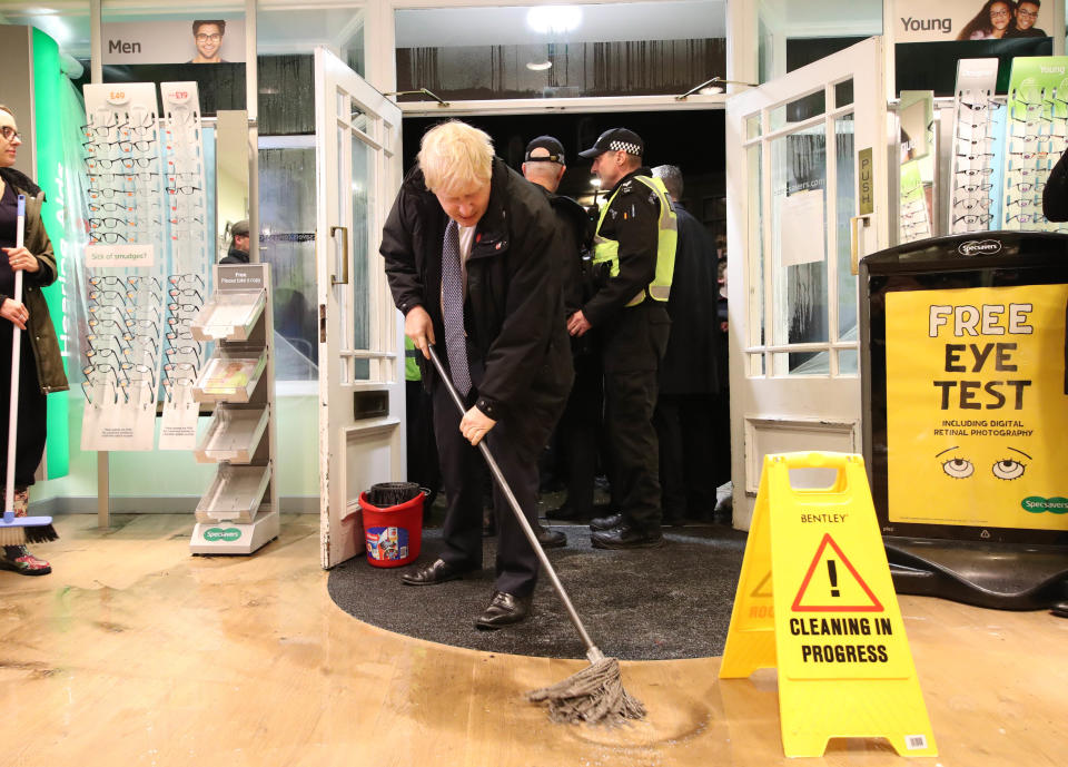 Britain's Prime Minister Boris Johnson helps with the clean up at an opticians in Matlock, northern England, on November 8, 2019 after it was effected by flooding. - Over a month's worth of rain fell on parts of England Thursday, with some people forced to evacuate their homes, and others left stranded in a Sheffield shopping centre. (Photo by Danny Lawson / POOL / AFP) (Photo by DANNY LAWSON/POOL/AFP via Getty Images)