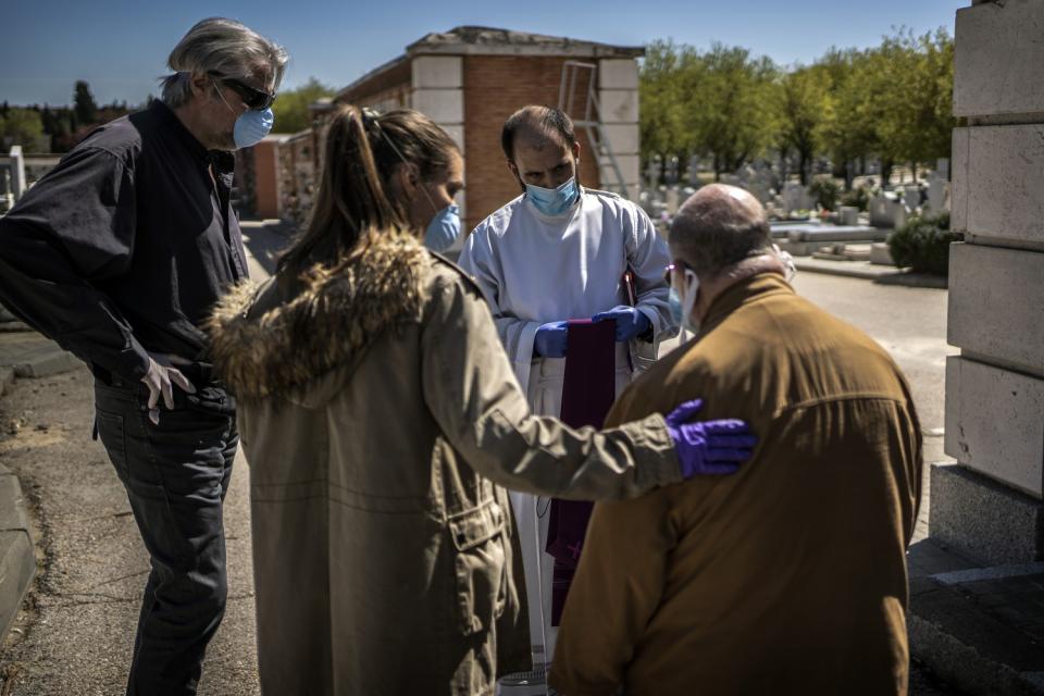 SPAIN: Family members talk to a priest before the burial of a loved one, a victim of COVID-19, at the Almudena cemetery in Madrid.