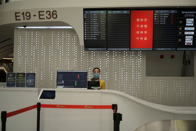 Una miembro del personal con máscara y gafas protectoras en un mostrador del Aeropuerto Internacional Beijing Daxing